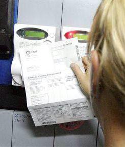 Una signora controlla la bolletta davanti ai contatori  