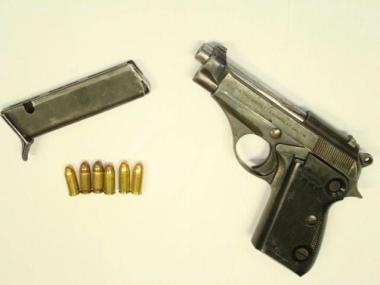 La pistola sequestrata e, a destra, i carabinieri di Aulla 