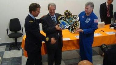 Gli astronauti Roberto Vittori e Greg Johnson consegnano a Valfredo Zolesi il simbolo della missione