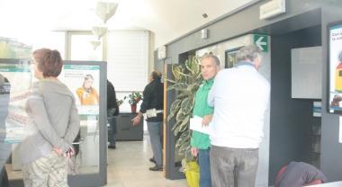 Il salone della banca con gli agenti che ascoltano impiegati e clienti A sinistra il bancone delle casse A destra un cliente legge il cartello «chiuso per rapina» e la polizia in piazza Matteotti