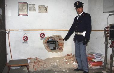 Un agente mostra il buco realizzato dai rapinatori 
