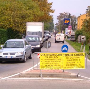 In alto via Ingrillini con i cartelli che annunciano la chiusura; sopra il passaggio a livello di via Fontanella 