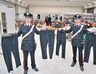 A sinistra i carabinieri mostrano i capi di abbigliamento recuperati nelle aziende 