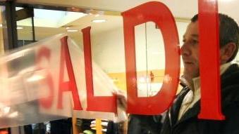 <b>IL COMMERCIO IN DIFFICOLTÀ.</b> Un negoziante applica alla vetrina l’adesivo che annuncia il via ai saldi