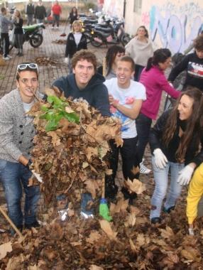 I ragazzi raccolgono le foglie nel giardino della scuola 