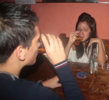 Giovani bevono alcolici in un pub. Sopra un ragazzino con la sigaretta 