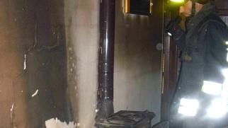 A destra la stufa a legna da cui è divampato l’incendio che ha poi causato la morte della pensionata e i vigili del fuoco che svolgono i primi rilievi dell’accaduto