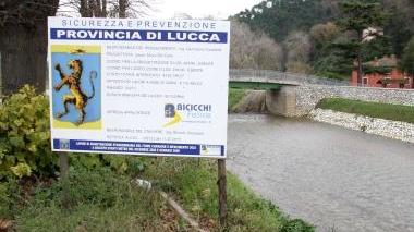 <strong>FIUME CAMAIORE.</strong> A sinistra il cartellone che annuncia i lavori sugli argini della Provincia per la messa in sicurezza; il fiume tra Ponte di Sasso e i Cavallini e a destra l’argine che verrà completamente rifatto con l’alveo raddoppiato. Sotto la strada lungofiume che sarà ridotta ad una semplice pista