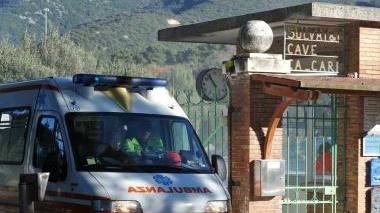 L’ambulanza lascia il luogo dell’incidente col ferito a bordo; a destra le cave di San Carlo