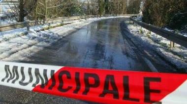 Viaggiatori dormono in branda all’aeroporto. Sopra tetti imbiancati, a destra un vigile urbano e il piazzale della stazione con la tenda per i soccorsi