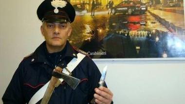 Un carabiniere mostra l’ascia e il coltello sequestrati