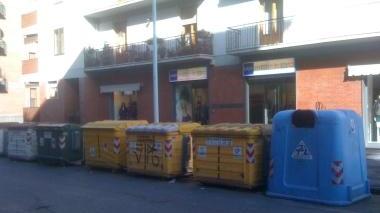 Un’immagine della fila di cassonetti davanti al negozio