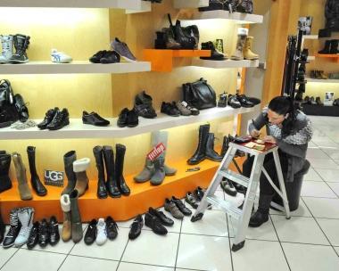 Sopra una commessa applica il cartellino a un paio di scarpe A lato il comandante dei vigili urbani Oliviero Billi