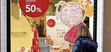 Da una vetrina occhieggiano gli sconti del primo giorno di saldi 