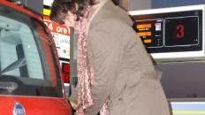 Una donna mentre rifornisce la propria auto ai carburante in un distributore self-service