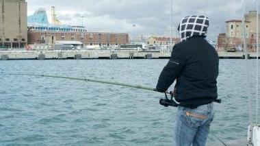 Un pescatore con la canna sul molo Elba