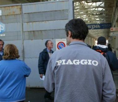 Operai davanti a uno degli ingressi nello stabilimento Piaggio 