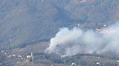 <strong>FIAMME.</strong> In alto, un incendio sulle colline di Camaiore Sopra, un vigile del fuoco al lavoro (Foto d’archivio)