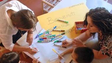 Il municipio di Vicopisano e in alto bambini in un asilo nido intenti a colorare con le loro insegnanti