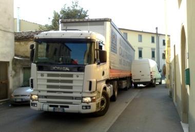 Un camion cerca di attraversare via Val dOrme facendo zig-zag tra unauto e un furgone 