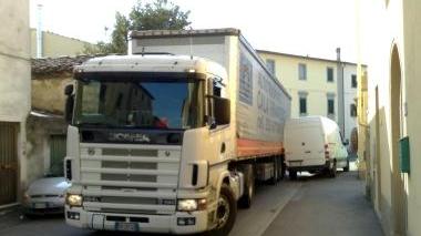 Un camion cerca di attraversare via Val d’Orme facendo zig-zag tra un’auto e un furgone