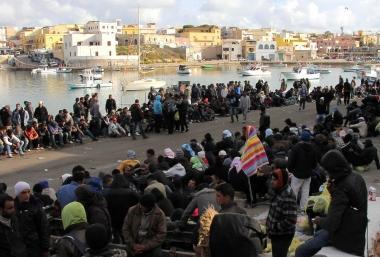 A sinistra il vescovo Simoni, sopra immigrati a Lampedusa