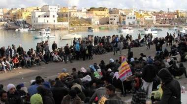 A sinistra il vescovo Simoni, sopra immigrati a Lampedusa