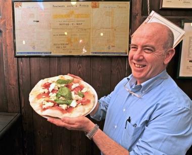 Stefano Parenti mostra una delle pizze del Pollo dOro A fianco il locale  