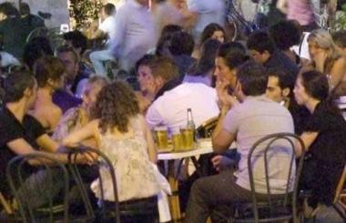 Alcuni avventori ai tavolini all’aperto di un bar