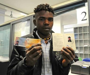 Un profugo mostra il passaporto appena consegnato Sopra altri tunisini in attesa del documento in Questura 