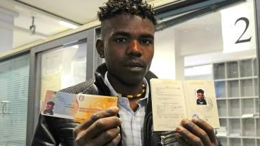 Un profugo mostra il passaporto appena consegnato Sopra altri tunisini in attesa del documento in Questura
