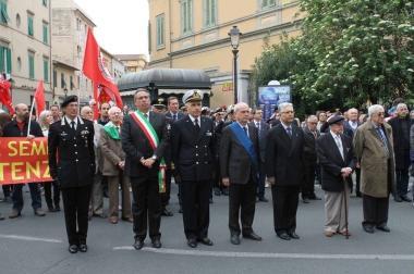 Le autorit&agrave; cittadine alla cerimonia e a destra la gente che canta Bella Ciao     