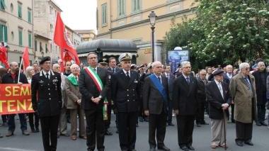 Le autorità cittadine alla cerimonia e a destra la gente che canta “Bella Ciao”