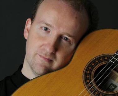 Pegoraro con la sua chitarra in primo piano 