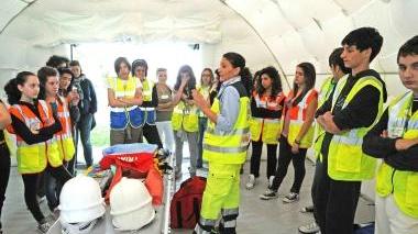 A lato, studenti in tenda ascoltano una lezione di Protezione civile Qui sotto i sindaci di Montale e Agliana, David Scatragli ed Eleanna Ciampolini