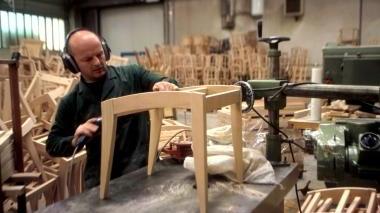Un falegname al lavoro all’interno di un’azienda che costruisce sedie in legno