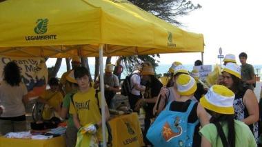 <b>FLASH.</b> Lo stand di accoglienza predisposto da Legambiente ai margini della spiaggia di Marina di Alberese, in collaborazione con il Parco della Maremma. Alcune ragazze intente alla raccolta sull’arenile e a destra una bottiglia recuperata sulle dune al confine con la macchia e la pineta