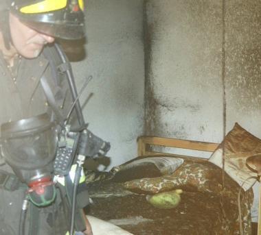 A sinistra i vigili del fuoco mentre terminano le operazioni di bonifica nella stanza incendiata. Sopra uno dei pompieri mentre entra nella palazzina di via Santo Stefano dove &egrave; divampato lincendio e a destra una foto del salotto, le cui pareti sono state danneggiate dal fumo.  