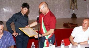 A fianco il giovane ciclista riceve la targa dal sindaco Tinti Sulla destra stringe la mano al maestro Luciano Bezzini Sotto &egrave; avvolto dal caloroso abbraccio di una signora 