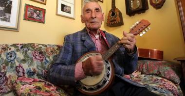 Sopra Brunetto Cantini suona la chitarra a sinistra mostra i suoi strumenti musicali e lalbum con le foto di una passione lunga pi&ugrave; di ottantanni  