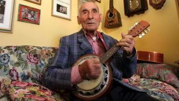 Sopra Brunetto Cantini suona la chitarra a sinistra mostra i suoi strumenti musicali e l’album con le foto di una passione lunga più di ottant’anni