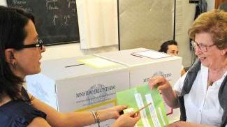 Una presidente di seggio consegna le schede ad un’elettrice