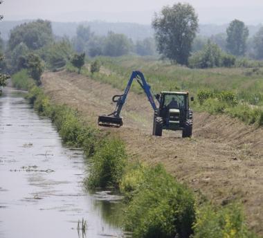 Una ruspa mentre effettua lavori di bonifica lungo un corso d’acqua