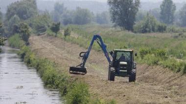 Una ruspa mentre effettua lavori di bonifica lungo un corso d’acqua