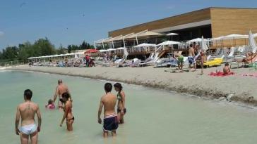 La struttura nata sulle rive del lago Braccini: all’interno c’è il bar, la pizzeria-ristorante e le cabine docce per i frequentatori di Amalia, la spiaggia cittadina A destra i lettini schierati al sole