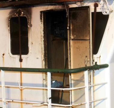Di lato la squadra dei vigili del fuoco impegnata sul ponte di comando della bettolina andata a fuoco          