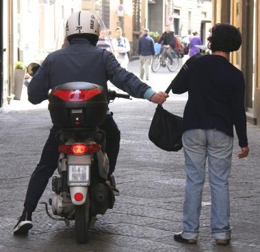 Una foto d’archivio che mostra uno scippatore in scooter che scippa una donna