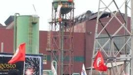 La protesta dei lavoratori sotto il silos dell’acciaieria (sullo sfondo) sul quale sono saliti tre operai