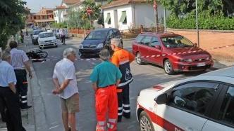 Via Fratelli Cervi a Perignano la strada dove si è verificato lo scontro tra lo scooter guidato da Deborah Tognaccini e una Opel. A destra il motorino della vittima a terra dopo l’impatto