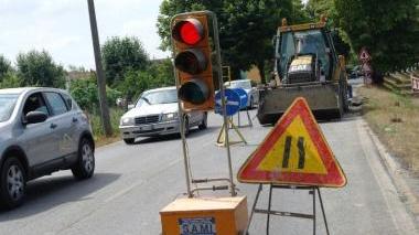 Il semaforo installato per regolare il senso unico alternato in via Orlandi. E sotto un operaio al lavoro